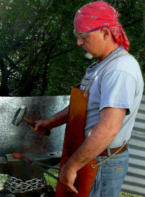 The knifemaker hand forging some Damascus